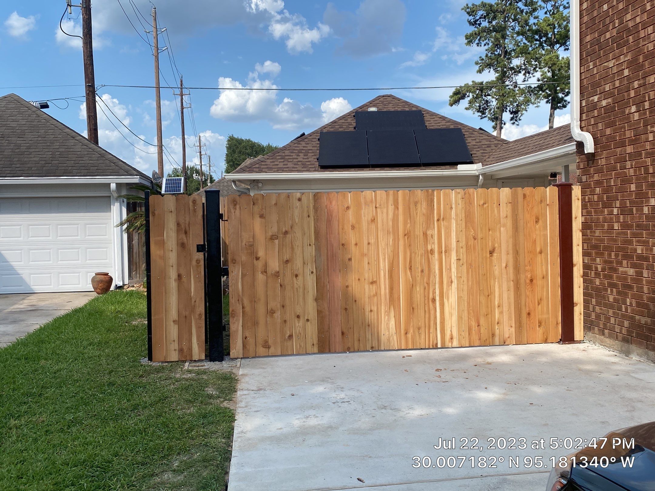 Complete metal driveway gate install with solar powered opener. Metal fence frame with Cedar Pickets by Astro Outdoor Designs 