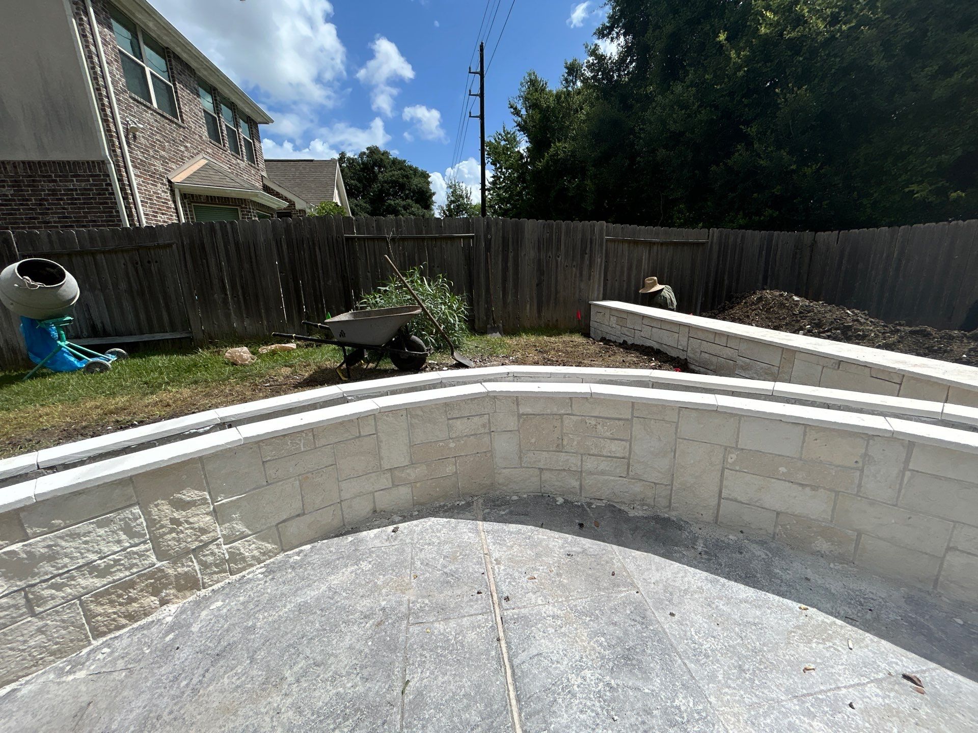 Major Transformation Project: Retaining Wall, Patio, and Drainage for Mr. & Mrs. Veerman! 🤩🛠️ We recently completed a comprehensive, custom project for Mr. & Mrs. Veerman that was all about structure, stability, and stunning outdoor design! This was a multi-phased project requiring the expertise of our Master Handcrafted Team.  Phase 1: Foundation and Water Management A successful outdoor space starts beneath the surface. We focused heavily on preparation and protection:  Demolition & Grading: We professionally removed and disposed of old dirt to achieve a level surface, ensuring the entire area was leveled and graded to enhance both appearance and functionality.  Comprehensive Drainage System: To prevent water issues and protect the new construction, we installed a complete system, connecting existing downspout gutters to channel drainage and strategically placed catch basins around the patio area.  Robust Concrete Foundation: Expert framing led to the pouring of a 4-inch deep, high PSI concrete slab to create a robust and lasting foundation for the entire retaining wall area.  Phase 2: Handcrafted Structure and Style This phase brought in our masonry and carpentry artisans to build the defining elements of the new space:  Custom Retaining Wall: Our master handcrafted team built a stunning, structural retaining wall. This involved careful framing, precise concrete work, and meticulous masonry construction with vertical supports every 3 feet for maximum stability.  Client Involvement: Mr. & Mrs. Veerman played a key role in selecting the retainer wall fascia and stone materials, ensuring the final look perfectly matched their vision.  Stamped Concrete Patio: We installed a beautiful stamped concrete patio. This decorative concrete work involved imprinting a pattern into the fresh concrete, giving them the high-end look of stone or brick with the durability of concrete.  Walk Add-On: Extended the stamped concrete to include a new, seamless walk area.  (Optional) Custom Garden Box: Constructed durable, raised garden boxes using 2"x12" boards and strong 4"x6" posts.  Phase 3: Landscaping and Finishing Touches The final details bring the entire project to life, focusing on irrigation and planting:  Sprinkler System Upgrade: To support their new landscaping, we upgraded their irrigation system by installing two new drip zones and a new control unit.  Flower Beds: Integrated new flower beds along the retaining wall and patio, ready for planting.  Decoration: Concluded the project with personalized decoration options to perfectly complement their beautiful, newly structured space.  Thinking About a Multi-Layered Outdoor Project? This project demonstrates our ability to seamlessly handle complex jobs—from heavy-duty drainage and structural construction to decorative finishes and irrigation.  The proposed timeline for this extensive project was 10 to 15 working days!  ❓ Do you have a sloping yard or drainage issues that could be solved with a functional and beautiful retaining wall? Tell us your challenge! 👇  💡 We specialize in bringing intricate outdoor visions to life! If you're looking for a team with master craftsmen for your next patio, retaining wall, or full landscape overhaul, let's talk. by Texas Urban Elements