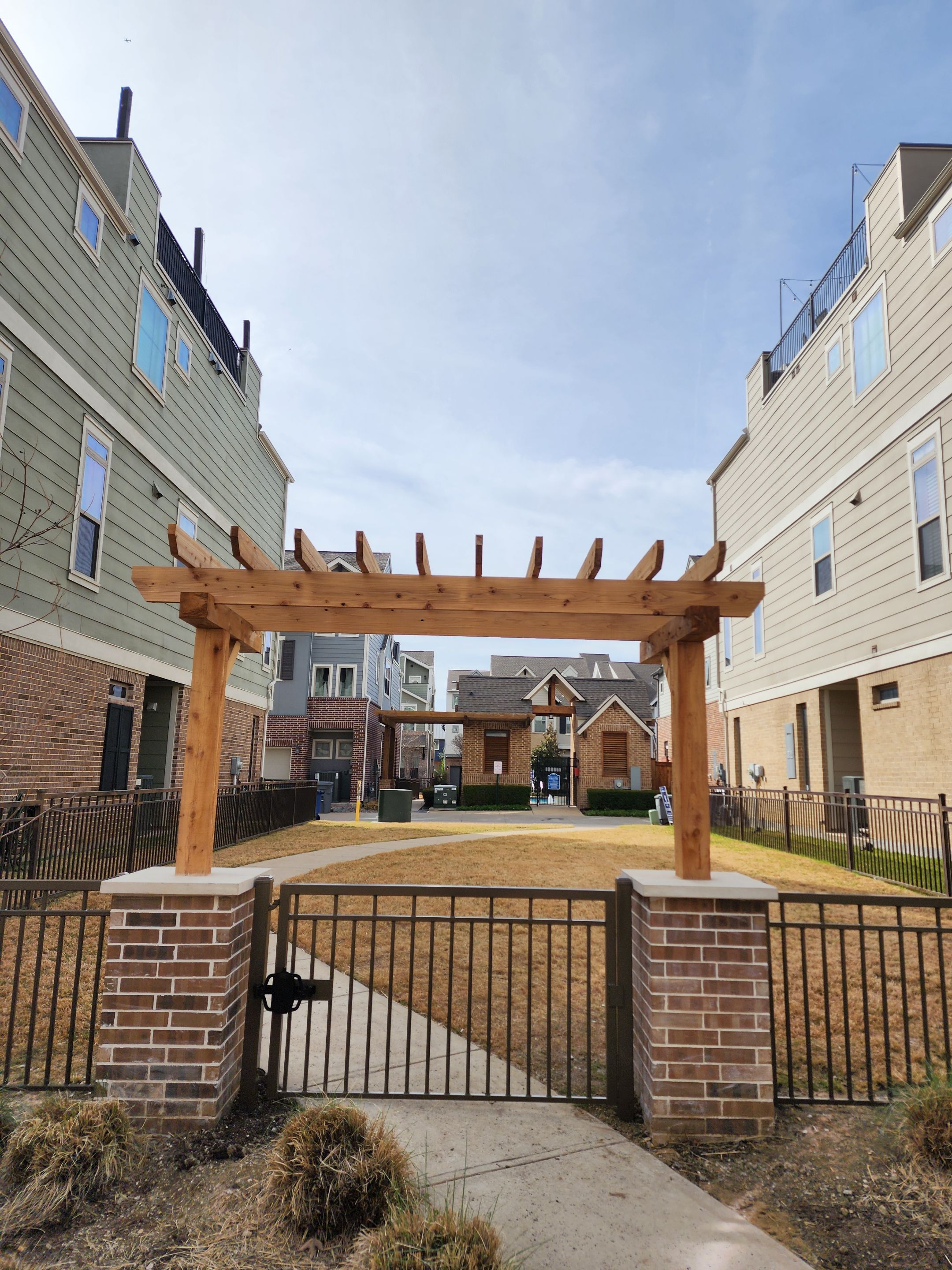 Arbor with Wrought Iron Fencing by 3:16 Roofing and Construction