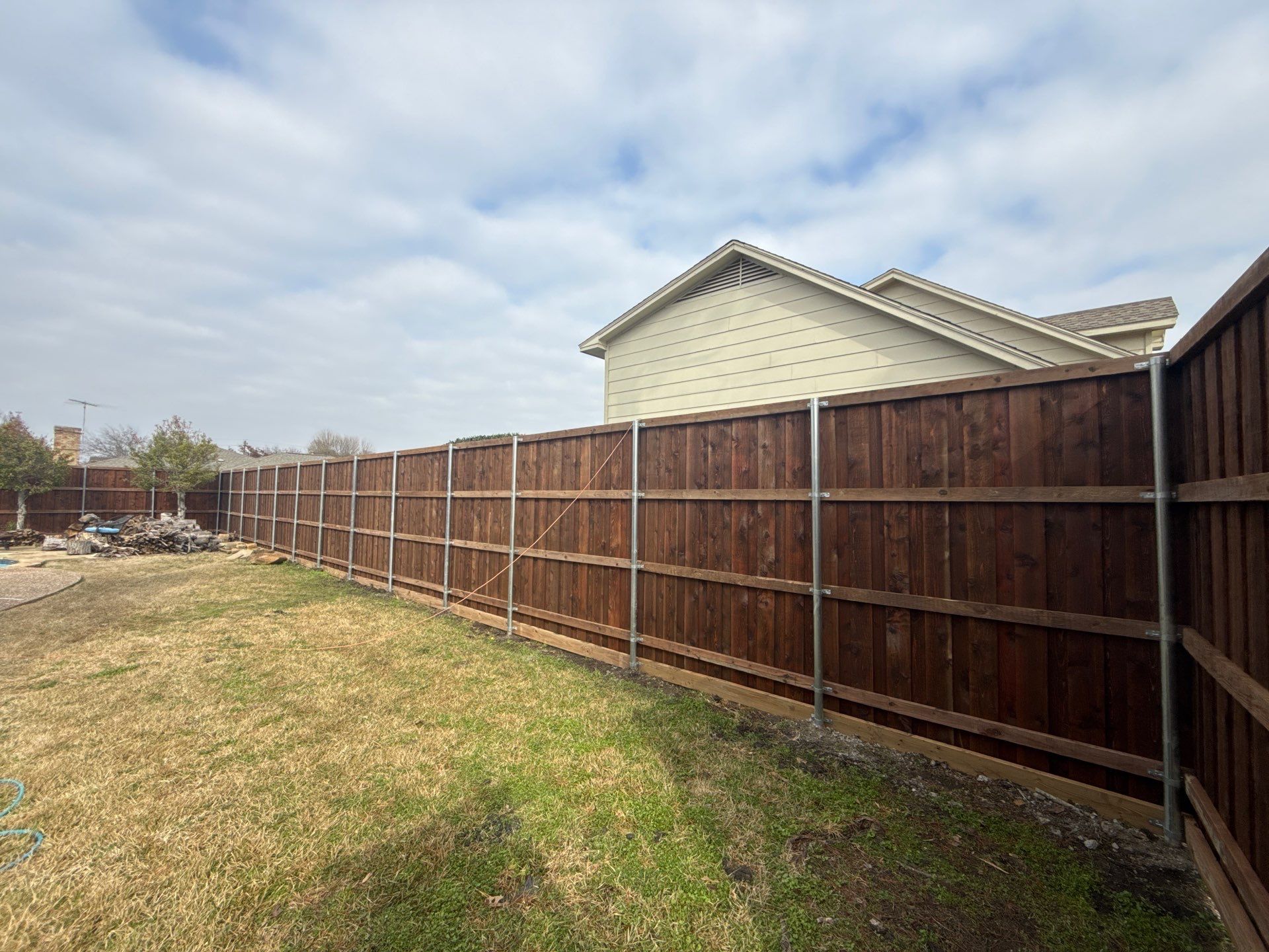 Pre-Stained board on board w/ trim and kickboard using 1x4 cedar trim by Grizzly Fence And Patio