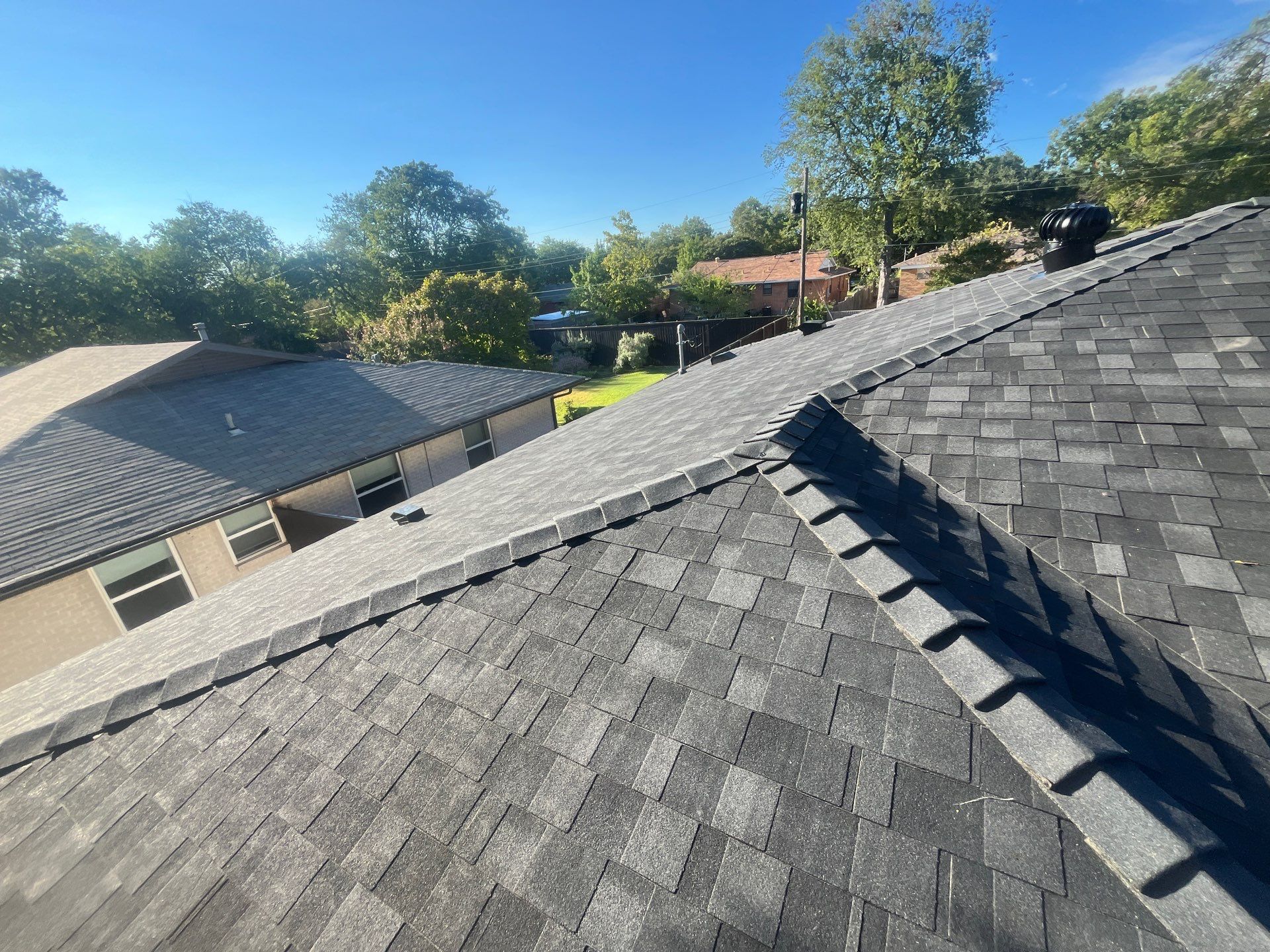 White brick/light gray shutters with IKO Granite Black  by Tejas Roofworks + Restoration