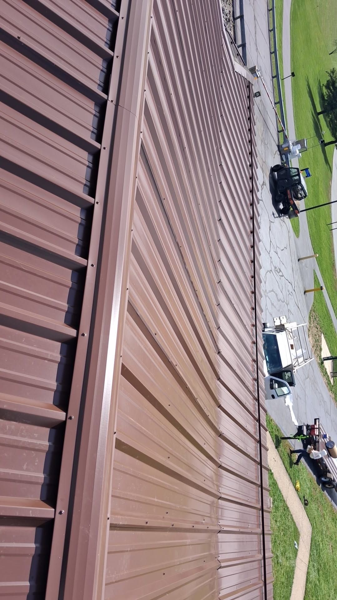 Brown R-Panel metal roof with solar by Atlas Roofing & Restoration