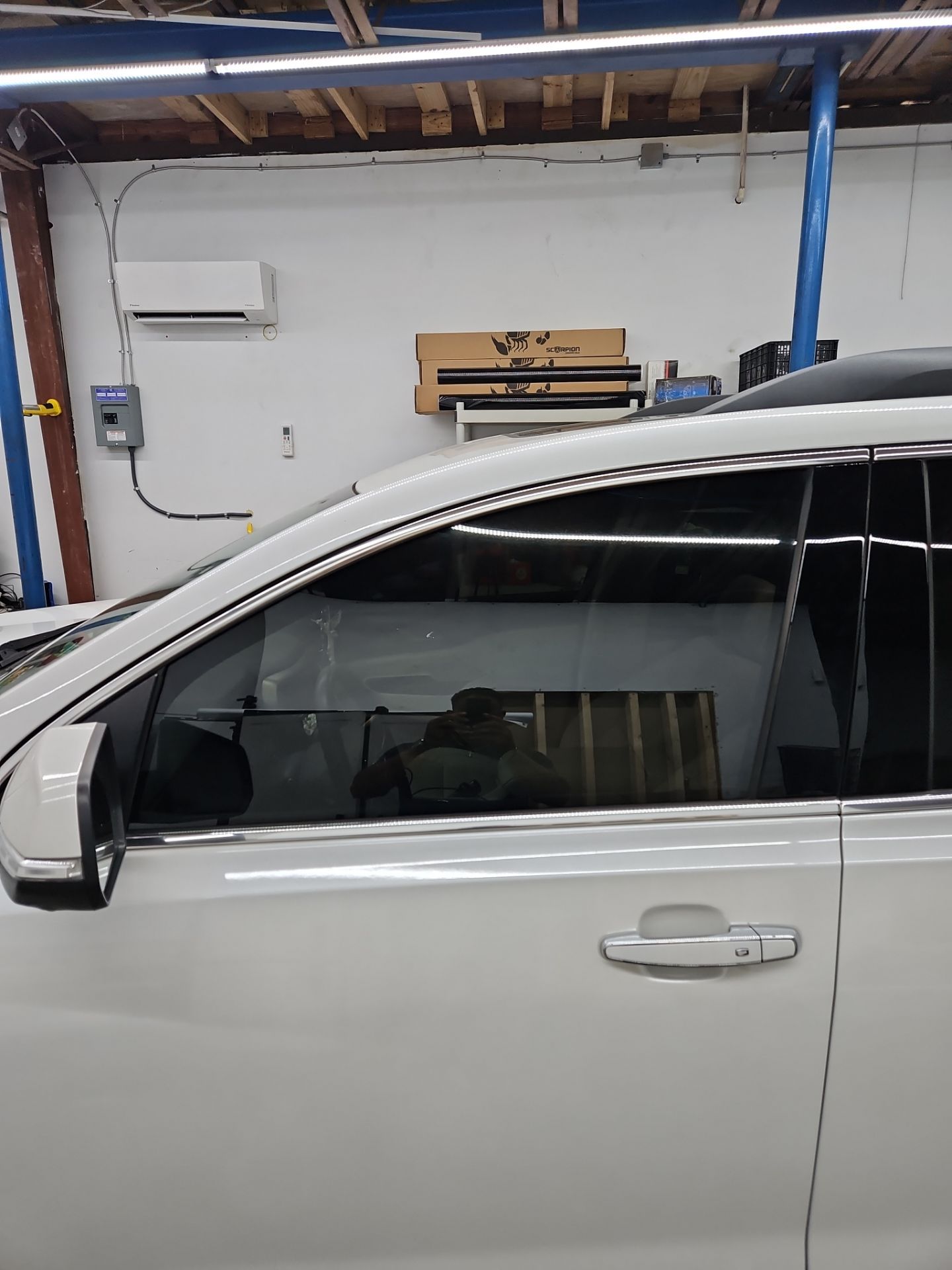 the service being done in the photo is window tinting on a light colored vehicle the tinted film is being applied to the side windows the tint helps reduce glare and heat while providing privacy the vehicle appears to be in a clean and organized workshop environment which is typical for this type of service